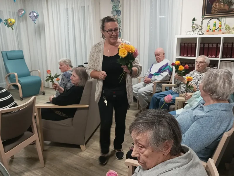 Eine Mitarbeiterin verteilt Rosen an die Bewohnerinnen nach der Theateraufführung.