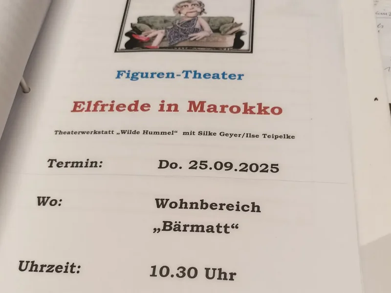 Ein Programmblatt mit dem Titel „Elfriede in Marokko“ zeigt Termin und Ort der Veranstaltung.
