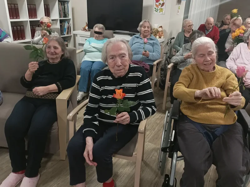 Mehrere Bewohnerinnen halten lächelnd bunte Rosen nach der Theateraufführung in den Händen.