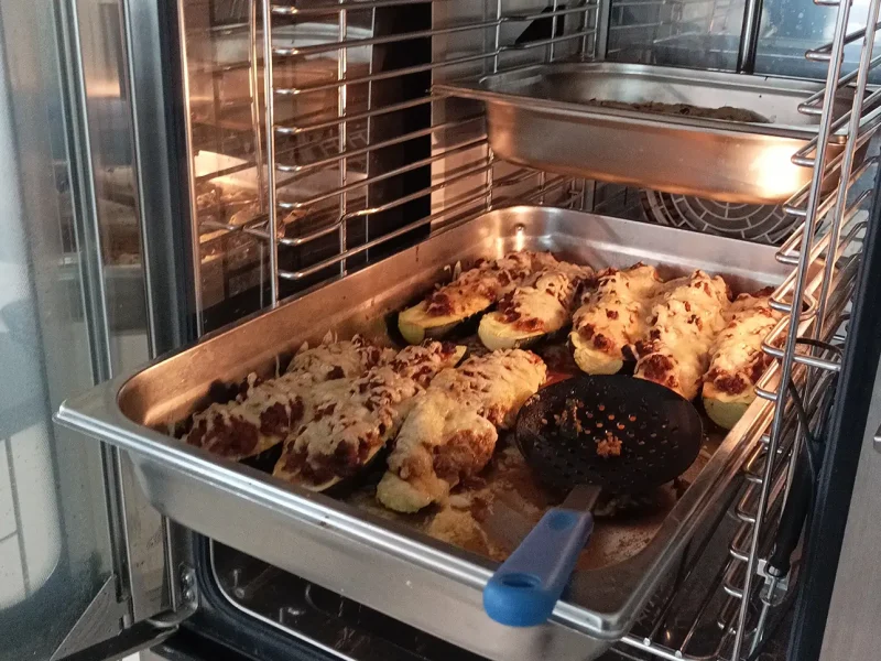 Eine Auflaufform mit überbackenen Zucchini im Ofen, bedeckt mit geschmolzenem Käse.