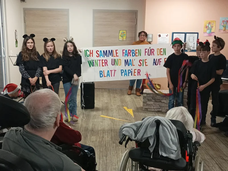 chüler stellen eine Szene aus der Geschichte der Maus Frederick dar und halten ein Banner mit dem Text über Farben für den Winter.