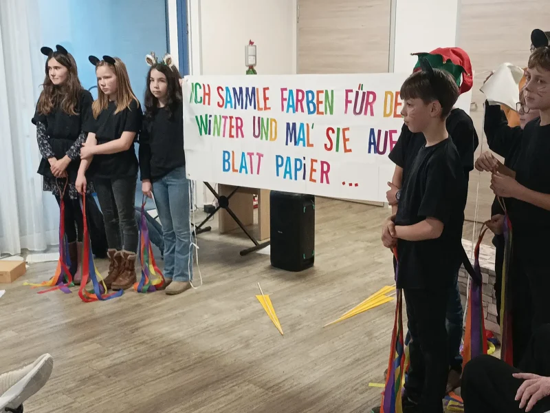 Schülerinnen und Schüler halten bunte Bänder als Symbol für Farben und Fantasie aus der Geschichte „Frederick“.